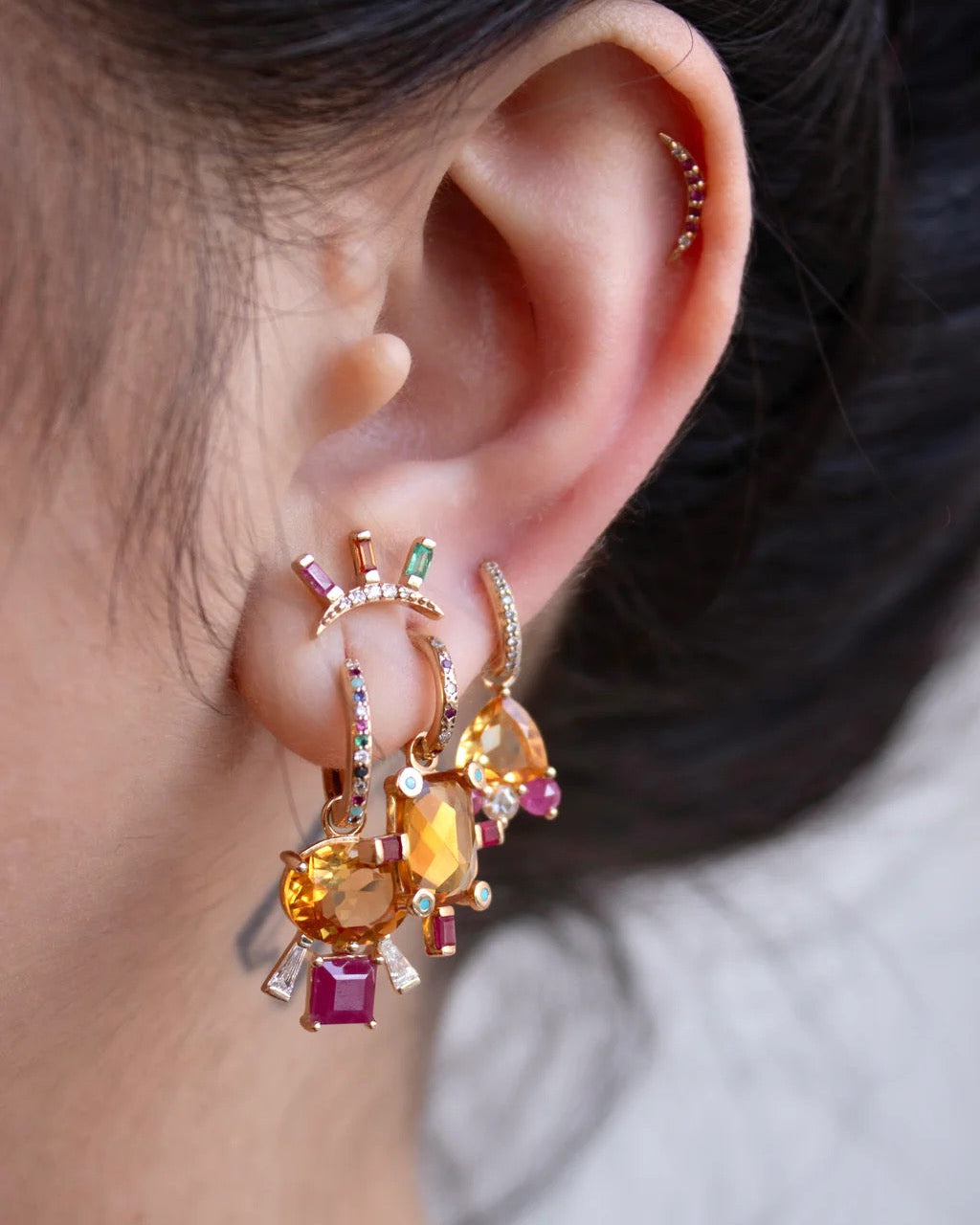 Close-up of an ear wearing a colorful earring with gemstones.